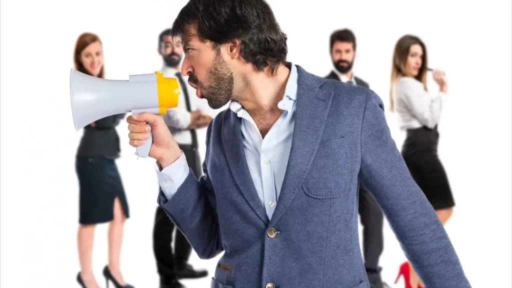 אדם במגה פון אומר משהו וקהל בחורות מאחוריו מקשיב